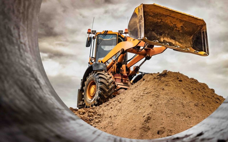 Powerful wheel loader or bulldozer working on a quarry or construction site. Loader with a full bucket of sand against the sky. Powerful modern equipment for earthworks